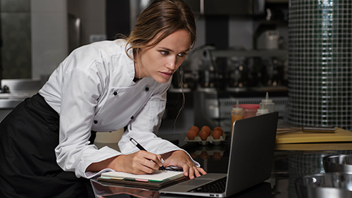 female chef kitchen using laptop device